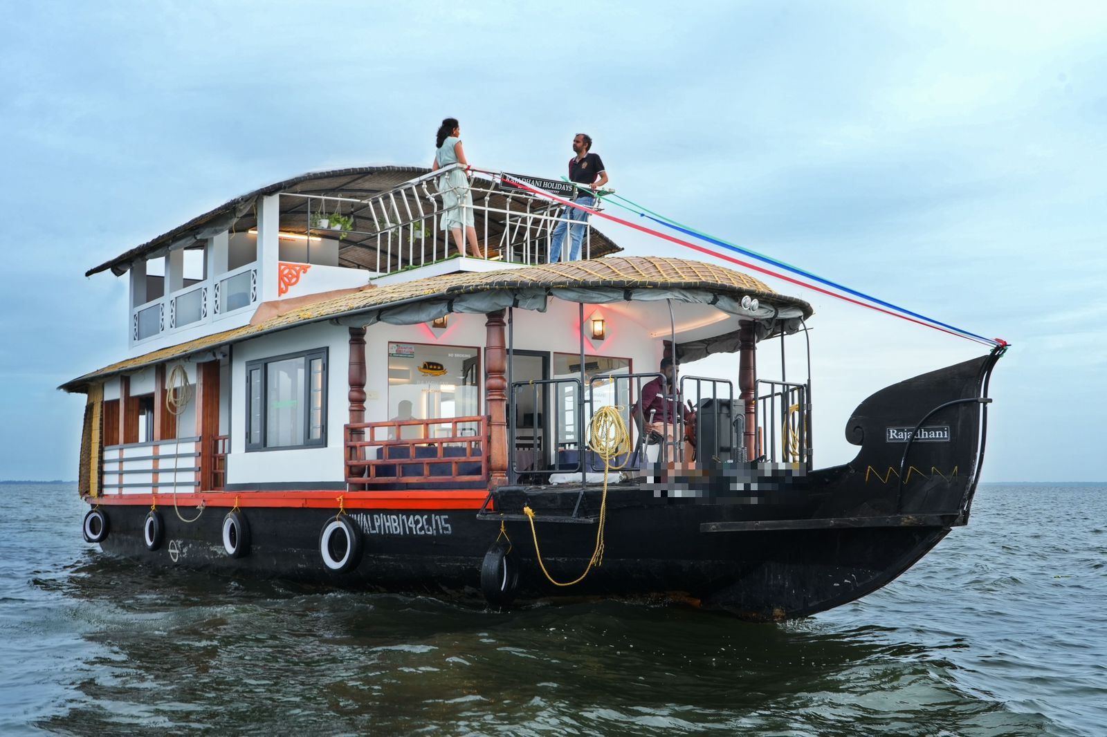 Two-deck houseboat with guests on the upper deck